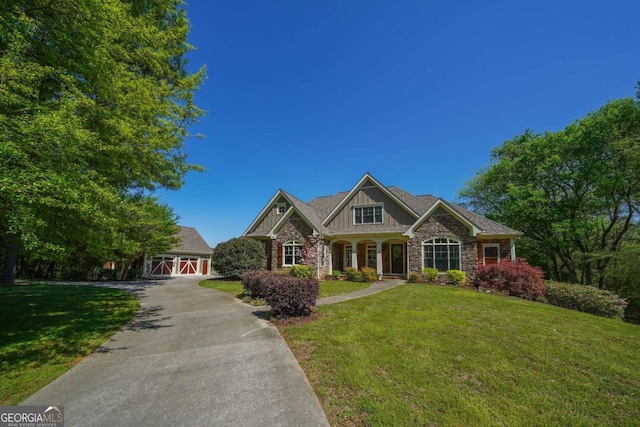 craftsman house featuring a barn, stone siding, aphalt driveway, a front yard, and an outbuilding