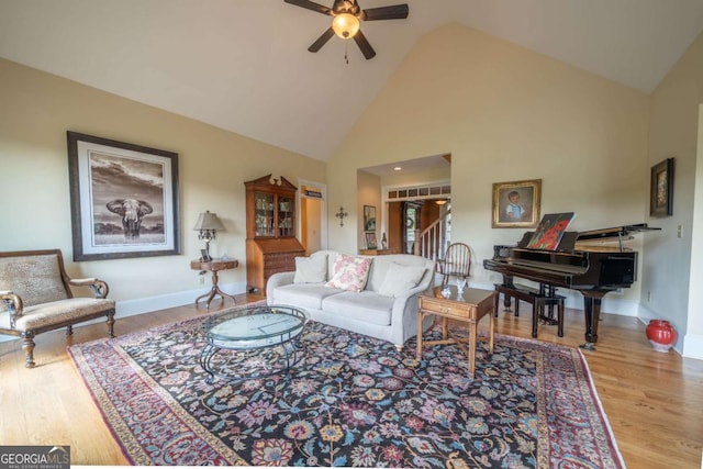 living area featuring high vaulted ceiling, baseboards, a ceiling fan, and wood finished floors