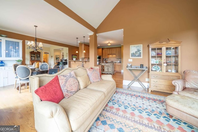 living room featuring light wood-style flooring, a notable chandelier, and vaulted ceiling