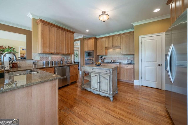 kitchen featuring crown molding, light stone countertops, light wood-type flooring, appliances with stainless steel finishes, and a sink