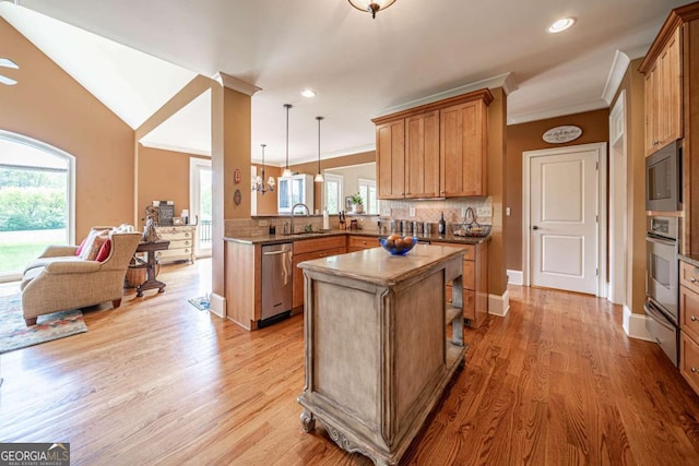 kitchen featuring a sink, open floor plan, light wood-type flooring, crown molding, and stainless steel appliances