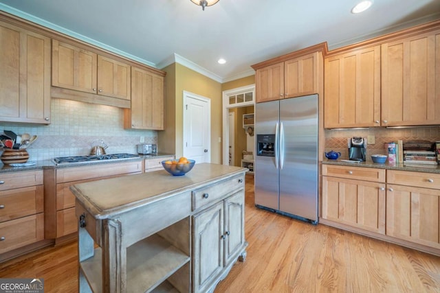 kitchen with tasteful backsplash, ornamental molding, appliances with stainless steel finishes, light wood finished floors, and a kitchen island
