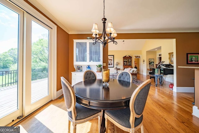 dining area with crown molding, baseboards, a chandelier, and light wood-style floors