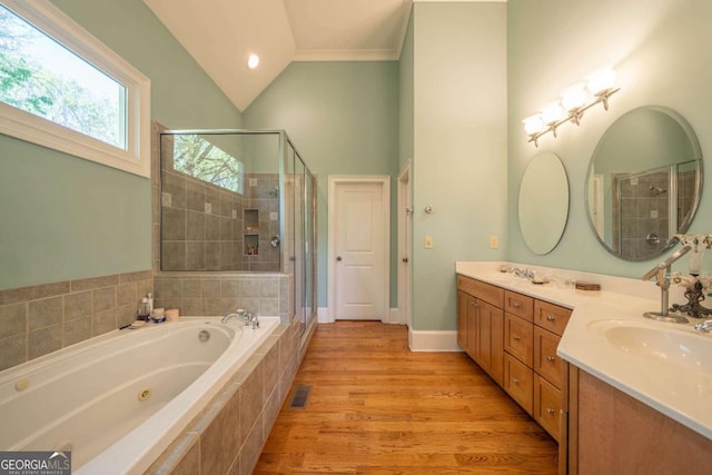 full bathroom with double vanity, a shower stall, a jetted tub, wood finished floors, and lofted ceiling