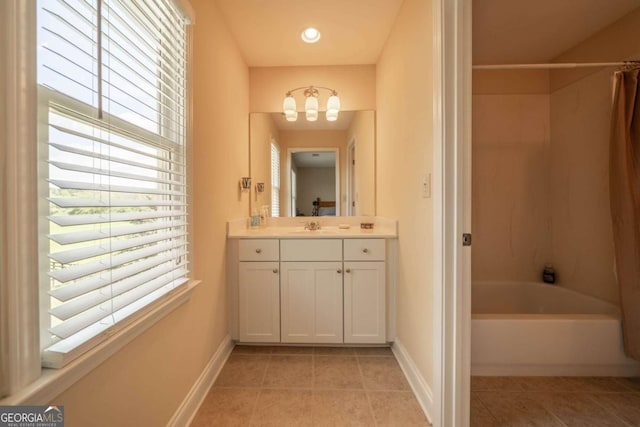 full bath with a chandelier, a wealth of natural light, tile patterned flooring, and baseboards