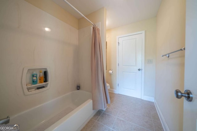bathroom featuring toilet, tile patterned floors, baseboards, and shower / tub combo with curtain
