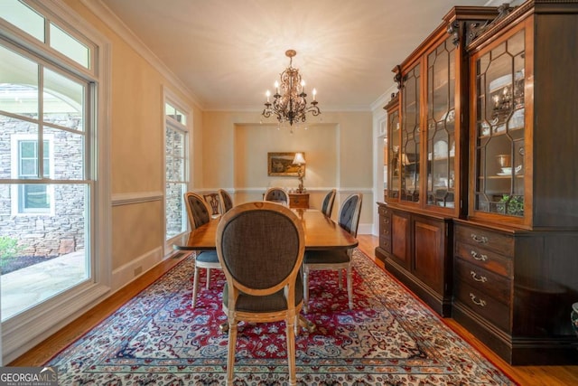 dining space with an inviting chandelier, crown molding, and wood finished floors