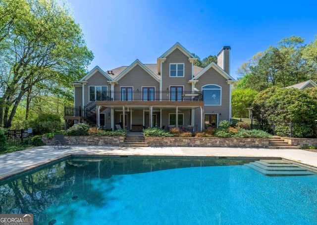 rear view of house featuring a fenced in pool, a patio, stairway, and a chimney