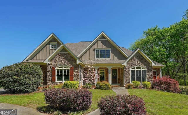 craftsman-style home featuring a front yard, board and batten siding, stone siding, and a shingled roof