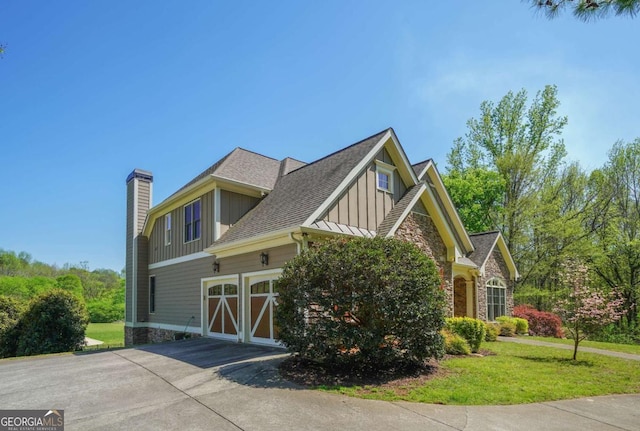 view of home's exterior featuring a lawn, a garage, board and batten siding, driveway, and roof with shingles