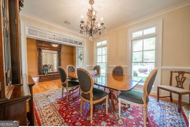 dining space featuring ornamental molding, a notable chandelier, and wood finished floors