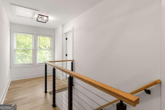 hall with baseboards, an upstairs landing, and light wood-style floors