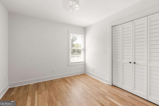unfurnished bedroom with a closet, light wood finished floors, and baseboards