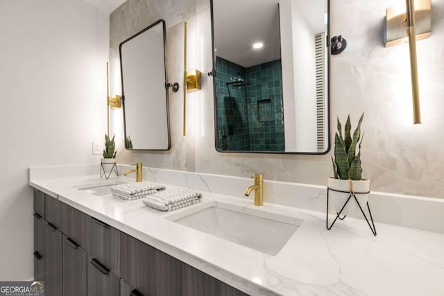 bathroom featuring tiled shower, double vanity, and a sink