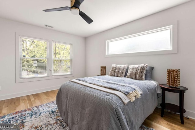 bedroom with wood finished floors, baseboards, a ceiling fan, and visible vents