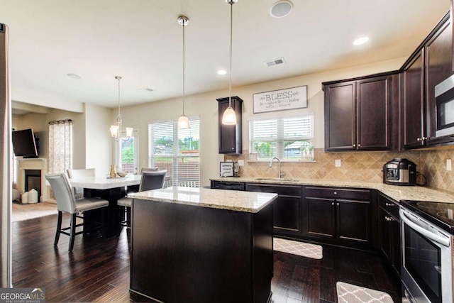 kitchen featuring a sink, light stone countertops, a kitchen island, and stainless steel electric range