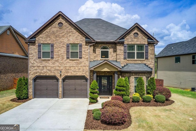 view of front of house featuring brick siding, driveway, an attached garage, and a front lawn