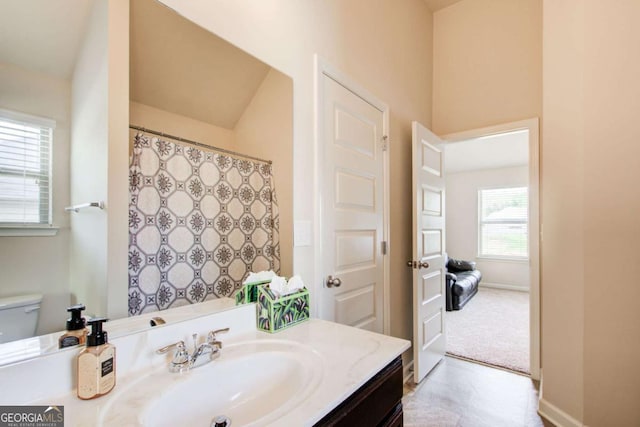 bathroom with toilet, vanity, and baseboards