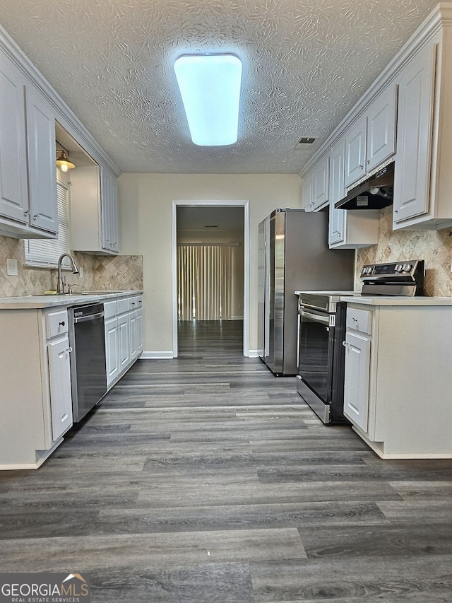4460 Branchwood Ct, Loganville, GA 30052 - kitchen with under cabinet range hood, light countertops, stainless steel appliances, decorative backsplash, and dark wood-style floors