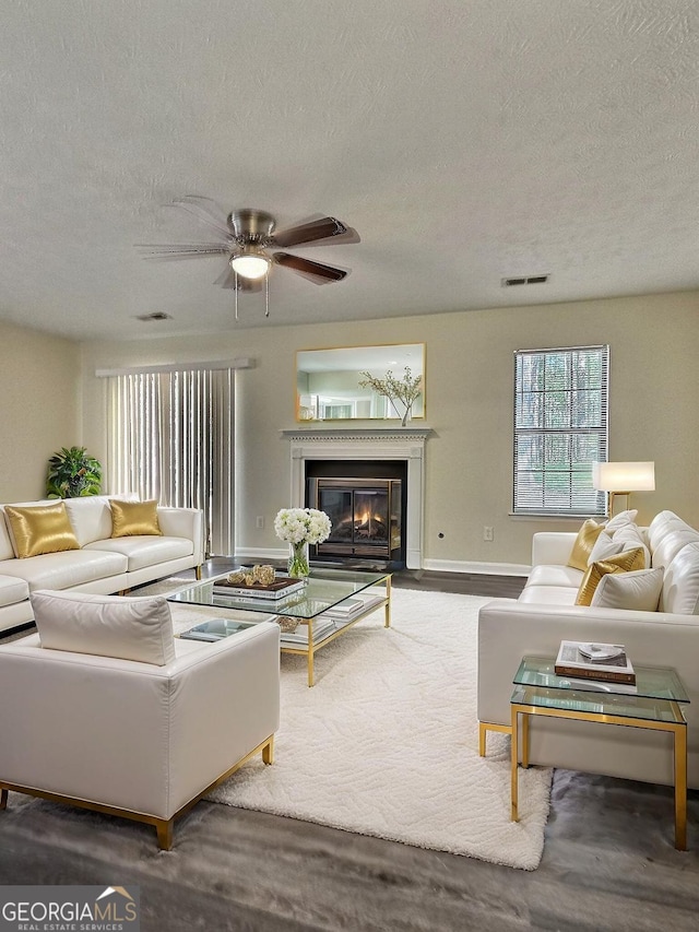 4460 Branchwood Ct, Loganville, GA 30052 - living area with a glass covered fireplace, a textured ceiling, a ceiling fan, visible vents, and wood finished floors
