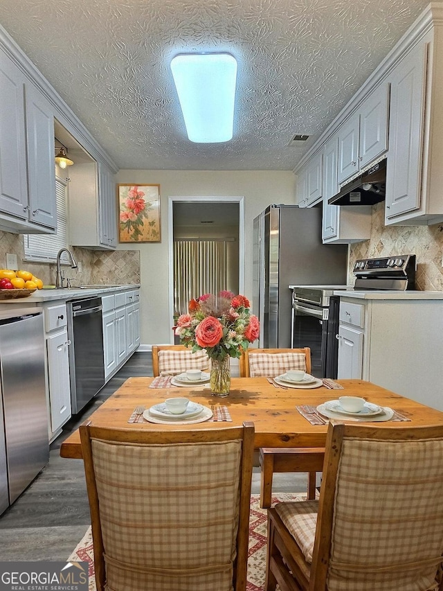 4460 Branchwood Ct, Loganville, GA 30052 - kitchen with tasteful backsplash, light countertops, under cabinet range hood, dark wood-type flooring, and appliances with stainless steel finishes