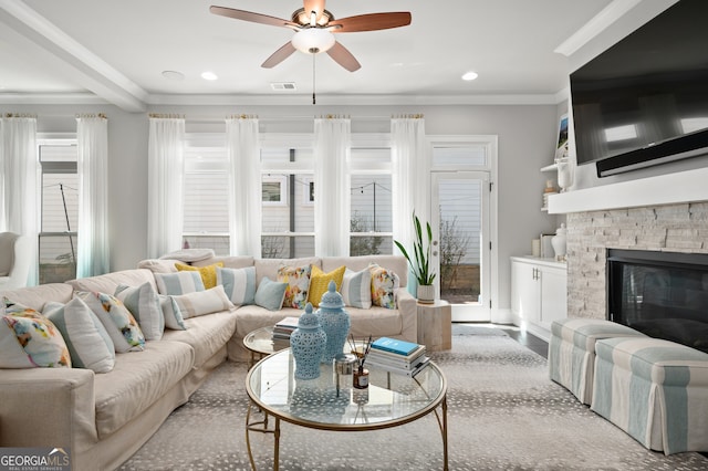 living room with visible vents, ornamental molding, a stone fireplace, ceiling fan, and recessed lighting