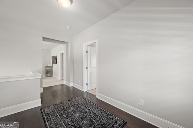 hall featuring an upstairs landing, baseboards, and dark wood finished floors