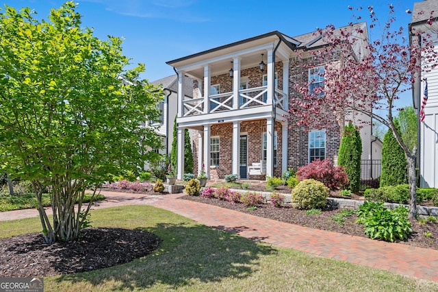 view of front facade featuring brick siding and a balcony
