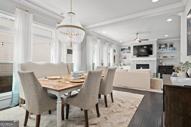 dining room with crown molding, ceiling fan with notable chandelier, a glass covered fireplace, recessed lighting, and wood finished floors