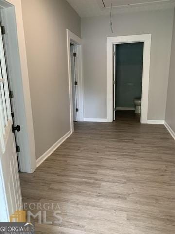 empty room featuring baseboards, attic access, and light wood finished floors