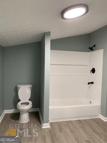 bathroom with baseboards,  shower combination, wood finished floors, and toilet