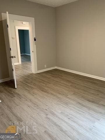 spare room featuring baseboards and wood finished floors