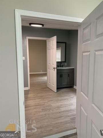 corridor with baseboards and light wood-type flooring