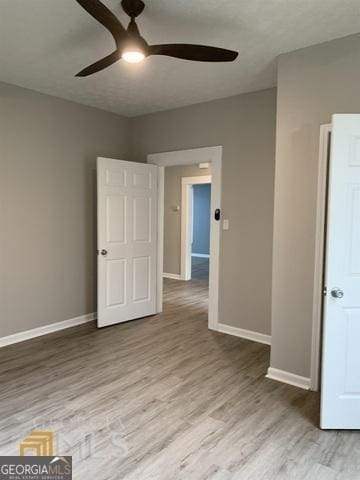 spare room featuring baseboards, a ceiling fan, and wood finished floors