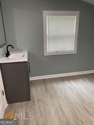 bathroom featuring baseboards, wood finished floors, lofted ceiling, and vanity
