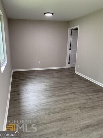 spare room featuring baseboards and wood finished floors