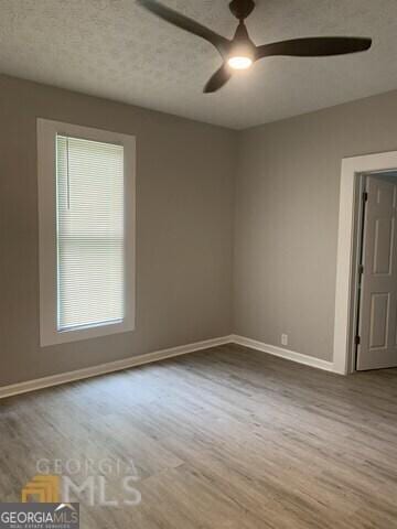 unfurnished room with baseboards, a ceiling fan, and wood finished floors