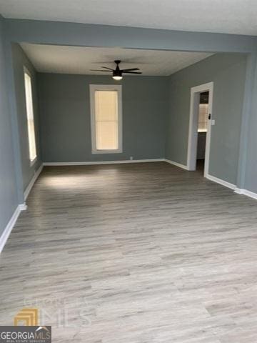empty room with baseboards, ceiling fan, and wood finished floors