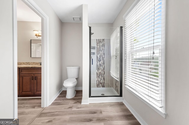bathroom with a shower stall, wood finished floors, vanity, baseboards, and toilet