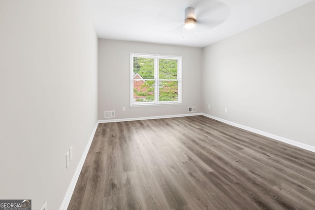 unfurnished room featuring baseboards, wood finished floors, and visible vents