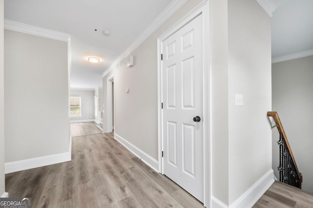 hall with baseboards, wood finished floors, an upstairs landing, and ornamental molding