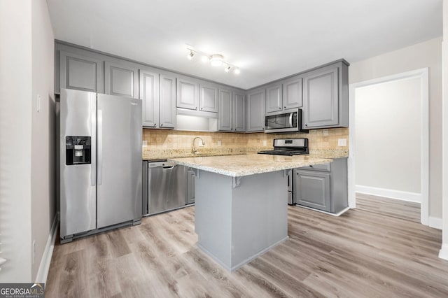 kitchen with tasteful backsplash, light wood-type flooring, gray cabinets, and stainless steel appliances