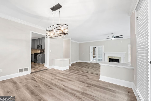 unfurnished living room featuring ceiling fan with notable chandelier, visible vents, a fireplace, and ornamental molding