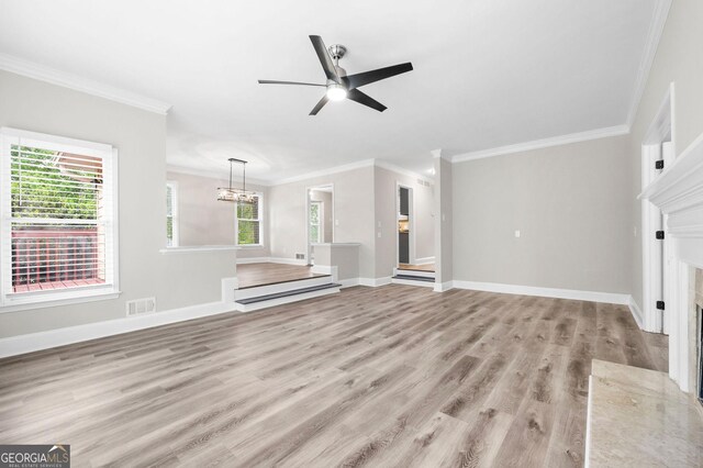 unfurnished living room featuring ceiling fan with notable chandelier, wood finished floors, visible vents, and ornamental molding
