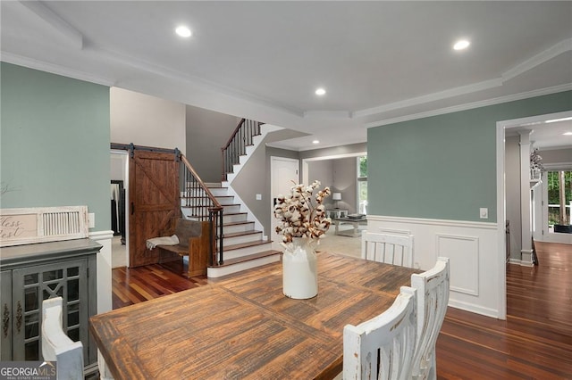 dining space with wainscoting, wood finished floors, stairway, and a barn door