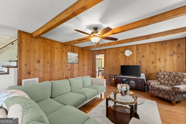 living area with visible vents, ceiling fan, a textured ceiling, beam ceiling, and wood finished floors