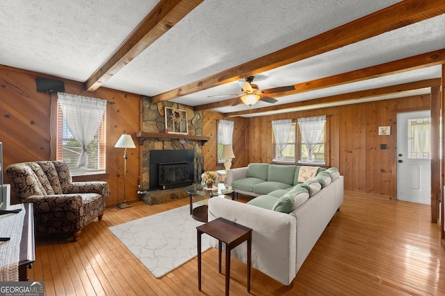 living room featuring a wealth of natural light, wood-type flooring, a textured ceiling, and beamed ceiling