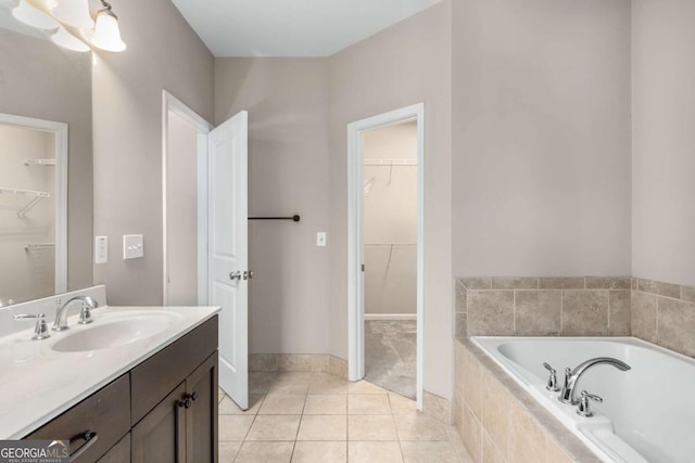 full bathroom featuring vanity, a walk in closet, tile patterned flooring, and a garden tub