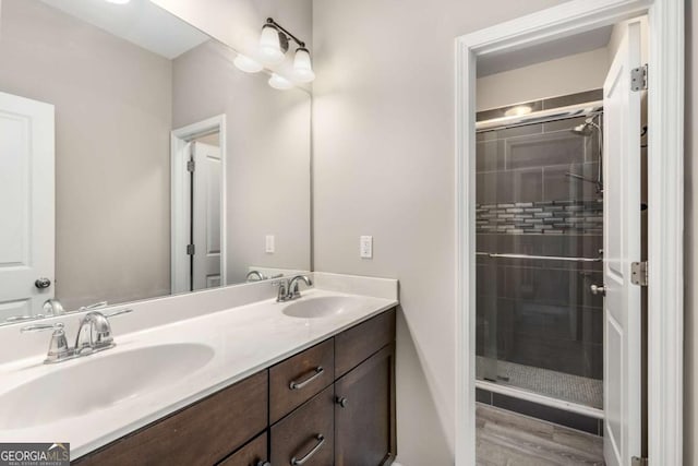 bathroom with a shower stall, double vanity, and a sink