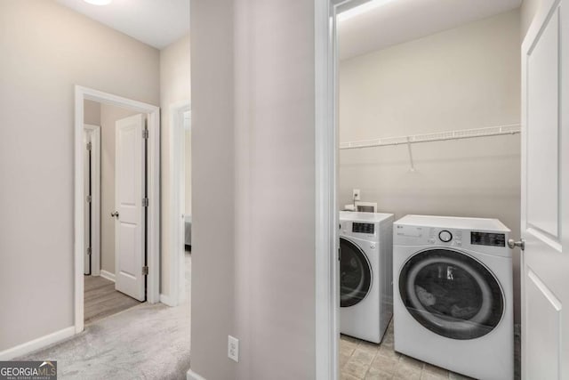 clothes washing area with light colored carpet, separate washer and dryer, laundry area, and baseboards
